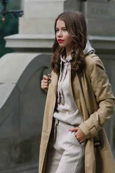 Retrato de mujeres de moda en traje deportivo beige y gabardina posando en la calle — Foto de Stock