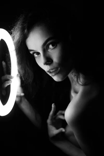 Retrato de estúdio emocional de uma jovem mulher em fones de ouvido sem fio com efeito flash de anel. Lâmpada de círculo LED redonda. — Fotografia de Stock