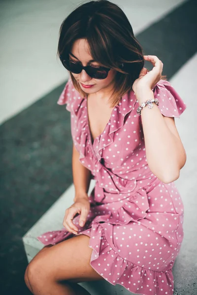 Jeune belle brune posant dans la rue dans une douce robe rose — Photo