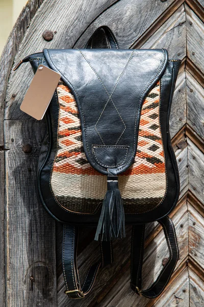 Svart läder ryggsäck med ett mönster på trädörren — Stockfoto