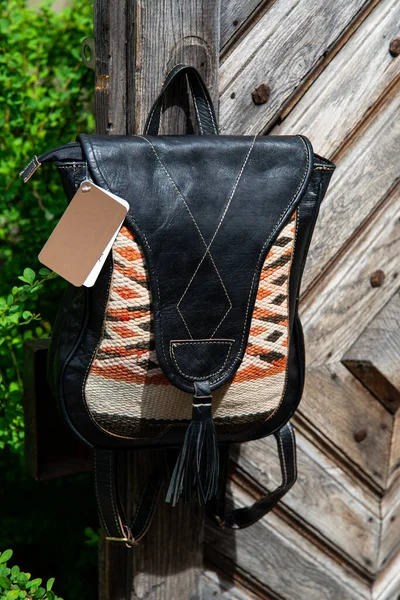 Black leather backpack with a pattern on the wooden door — Stock Photo, Image