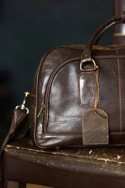 Leather brown travel bag, on a brown leather chair — Stock Photo, Image