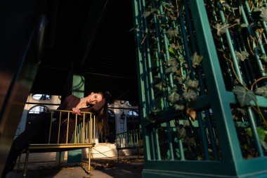 Uzun bacaklı, şık, esmer bir kadının portresi. Uzun kollu, sağlam bir vücut giysisi. Tek parça tulum.