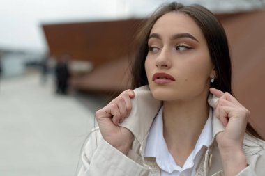 Şık bir ceket giyen güzel, şık bir hanımın açık hava portresi. Manken yan bakıyor. Kadın moda konsepti. Şehir yaşam tarzı. Kapat..