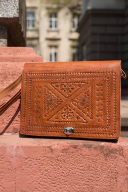 small orange womens leather bag with a carved pattern
