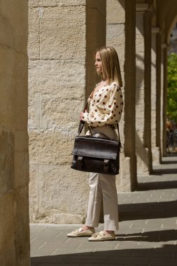 Antika ve antika görünümlü kahverengi deri çantalı bir kadın. Açık hava fotoğrafı.