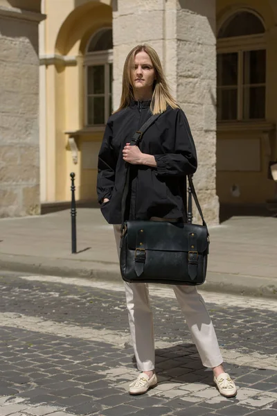 Antika ve antika görünümlü siyah deri çantalı bir kadın. Açık hava fotoğrafı.