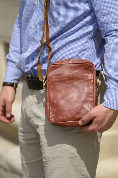 Close-up photo of a small orange leather bag in mans hand — Stok fotoğraf