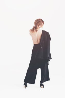 Ceket ve iç çamaşırı giymiş genç bir kadın. Ceketli, pantolonlu ve seksi iç çamaşırlı bir kız stüdyoda poz veriyor.