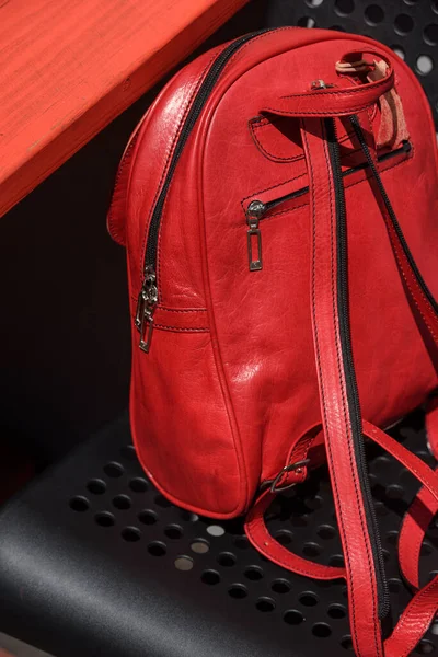 Red leather casual unisex backpack on a black chair. Outdoors photo
