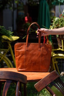 close-up photo of orange leather bag on a wooden table. outdoors photo