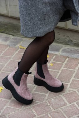 Womens autumn pink suede ankle boots. side view. Fashion shoes. Outdoors. stone pavement