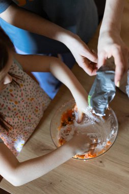 Anne ve kızı balkabaklı kekler üzerinde hamur yoğurur.