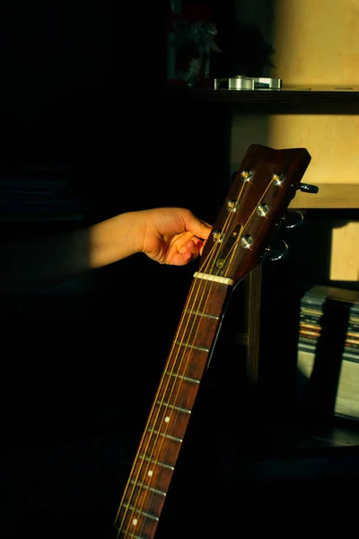 Une fille écoute une guitare dans le noir. Concept d'apprentissage de la musique. — Photo