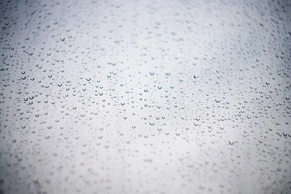 Raindrops on glass or window shot at an angle on a light transparent background — Stock Photo, Image