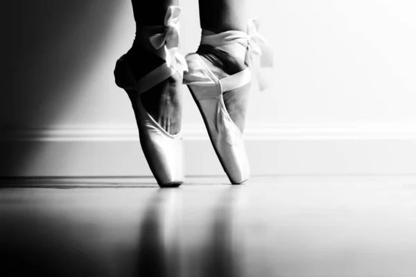 The ballerina stands on pointe in the studio. Black and white photo. — Stock Photo, Image