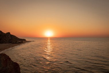 Deniz kıyısında gün batımı. Kayalar ve deniz.