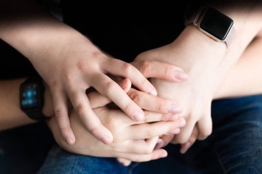 Karanlık bir arka planda anne ve çocukların elleri birbirine dolanmış. Aile sigortası kavramı.