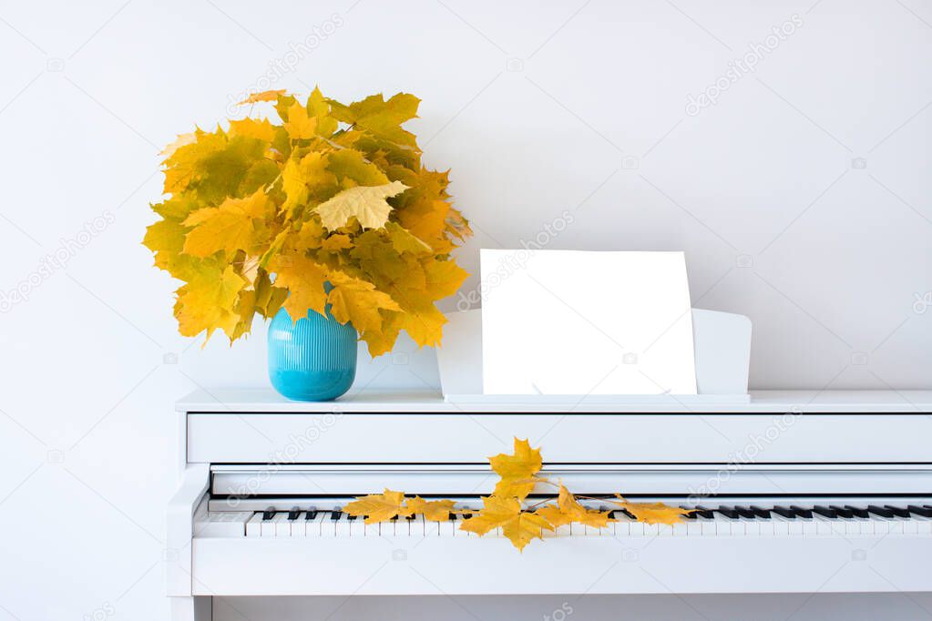 Maple leaves on the piano in a blue vase. The concept of autumn. Isolated.
