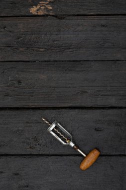 Şarap açmak için tirbuşon koyu ahşap bir arka planda yatıyor..