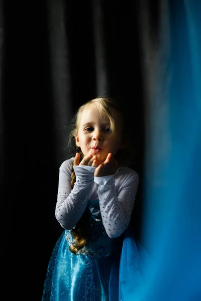 Portrait d'une petite fille envoyant un baiser d'air sur un fond bleu foncé. — Photo
