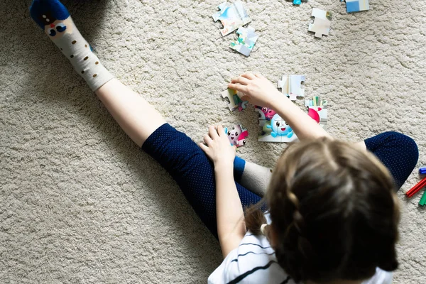 A girl plays in her room, collects a jigsaw puzzle. — Stock Photo, Image