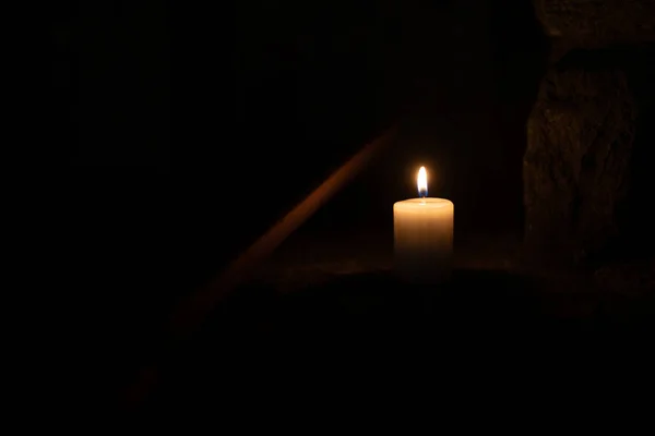 Een kaars brandt tegen de achtergrond van metselwerk in het donker. — Stockfoto