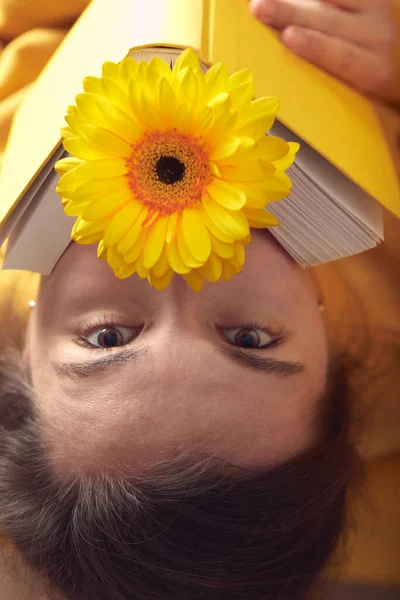 Sarı kitabı ve Gerbera çiçeğiyle güzel bir kızın portresi.. — Stok fotoğraf