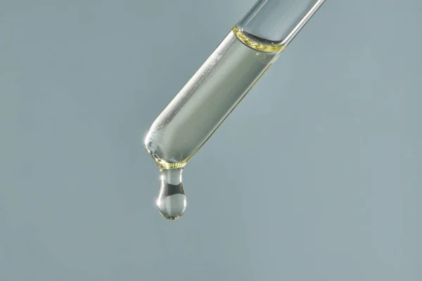 Een druppel cosmetische aromatische olie druipt uit de pipet. — Stockfoto