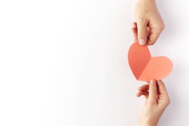 Sevgililer Günü, kağıttan yapılmış kırmızı kalp birbirine aşık bir çiftin elinde tutulur. Uzayı kopyala Metin için yer.