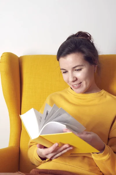 Uma mulher bonita com um livro em sua cadeira. — Fotografia de Stock