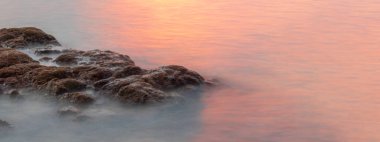 Akşamları ya da sabah erken saatlerde denizin ortasındaki kayalar arka plan görüntüsü olarak kullanılabilir. Sağ tarafta, doğal deniz ya da jeoloji hakkında mesaj bırakmak için boş bir alan var..