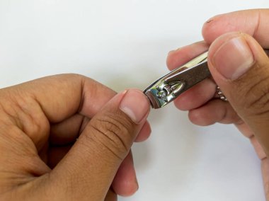 Adamın eli beyaz arka planda tırnak kesiyor.