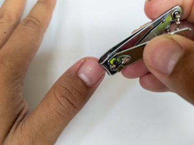 Adamın eli beyaz arka planda tırnak kesiyor.