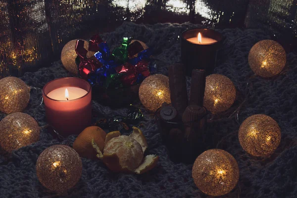 圣诞节还有糖果 两支蜡烛 一个用线织成的球形式的花环 静谧的生活在一条针织围巾上 这给了照片一种氛围和舒适感 背景亮晶晶 — 图库照片