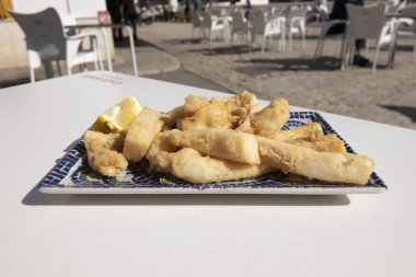 Kızarmış mürekkep balığı şeritleri, İspanyolca Chocos Fritos. Dekoratif dikdörtgen bir tabakta servis edilmiş. İspanyol gıda konsepti.