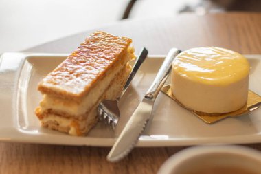 Bir tabak puf böreği ve limonlu pasta, keklerin arasında bir çatal ve bir bıçak..