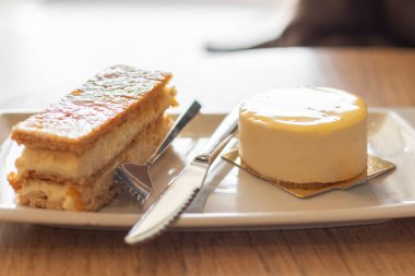 Bir tabak puf böreği ve limonlu pasta, keklerin arasında bir çatal ve bir bıçak..