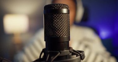 Mutlu Asyalı bayan blogger müzik etkeni bilgisayarda kulaklıklı bir podcast ve oturma odasındaki ev stüdyosunda izleyicilerle mikrofon konuşması kaydediyor. Evde kal, içerik yaratıcısı konsepti.