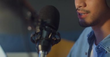 Mutlu Asyalı adam blogger müzik etkeni bilgisayarda kulaklıklı bir podcast ve oturma odasındaki ev stüdyosunda izleyicilerle mikrofon konuşması kaydediyor. Evde kal, içerik yaratıcısı konsepti.