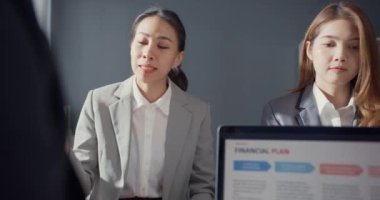 Genç Asyalı iş adamları ve iş kadınları, ortağıyla birlikte çalışarak küçük modern ev ofisinde takım çalışmasının tadını çıkarıyorlar..