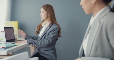Bir grup Asyalı yaratıcı grup, çalışma masasında çalışırken ve iş yerindeki ofis masasında iletişim kurarken evrak ve dizüstü bilgisayardaki noktaları karşılaştırmak için projeyi tartışıyor. Ortak işbirliği, iş arkadaşı takım çalışması.
