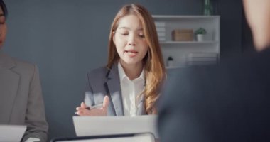 Genç Asyalı iş adamları ve iş kadınları, ortağıyla birlikte çalışarak küçük modern ev ofisinde takım çalışmasının tadını çıkarıyorlar..