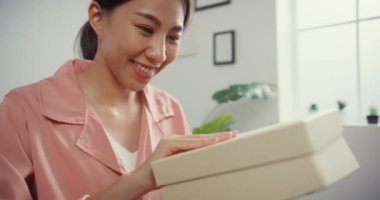 Mutlu Asya 'lı güzel bayan evdeki oturma odasındaki çevrimiçi pazardan karton teslimat paketini açıyor. İnternet üzerinden alışveriş yapan, boks yapmayan, online alışveriş ve dağıtım konsepti olan.