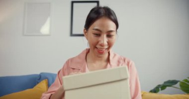 Mutlu Asya 'lı güzel bayan evdeki oturma odasındaki çevrimiçi pazardan karton teslimat paketini açıyor. İnternet üzerinden alışveriş yapan, boks yapmayan, online alışveriş ve dağıtım konsepti olan.