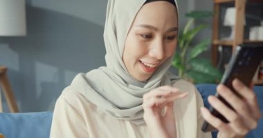 Çekici, genç, Asyalı, tesettürlü, tesettürlü, neşeli, genç, Müslüman bir kadın. Telefonunu kullan ve evdeki rahat oturma odasında online alışverişin tadını çıkar. Kız İslam yaşam tarzı kavramını karantinaya aldı.