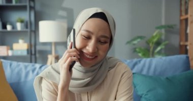 Çekici, neşeli, Asyalı, genç, Müslüman, tesettürlü güzel bir kadın. Evdeki rahat oturma odasında arkadaş ve aileyle gündelik telefon görüşmesi yapıyor. Kız İslam sosyal mesafesi yaşam tarzı kavramını karantinaya aldı.