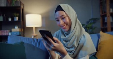 Çekici, genç, Asyalı, tesettürlü, tesettürlü, neşeli, genç, Müslüman bir kadın. Telefonunu kullan. Geceleri evdeki rahat oturma odasında online alışverişin tadını çıkar. Kız İslam yaşam tarzı kavramını karantinaya aldı.