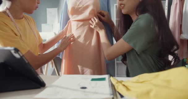 特写行业亚洲女性设计师团队精神最后会见样衣新品收藏共享理念在商店里 年轻裁缝在办公桌前的车间里讨论新布料的颜色 协作的概念 — 图库视频影像
