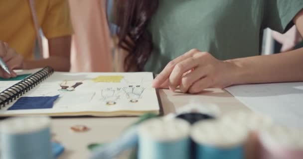 特写行业亚洲女性设计师团队合作会速写本关于新藏品共享理念的工作在商店里进行 年轻裁缝在餐桌上讨论新布料的颜色 协作的概念 — 图库视频影像